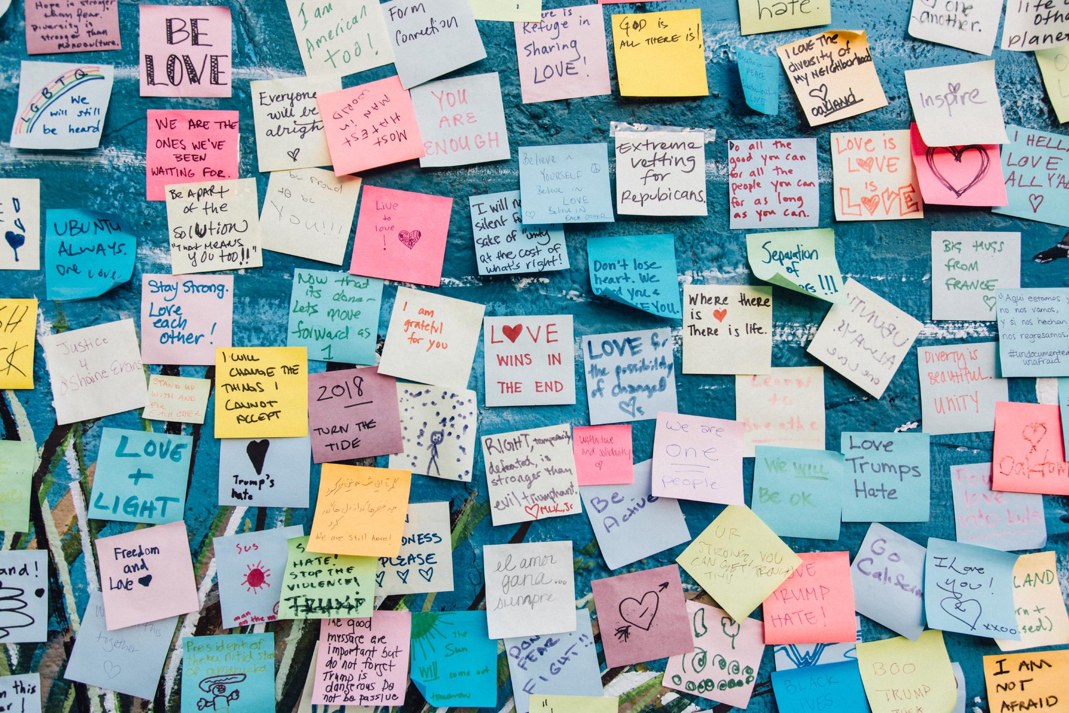 a wall full of colorful post-it notes with various pro-love anti-hate messages