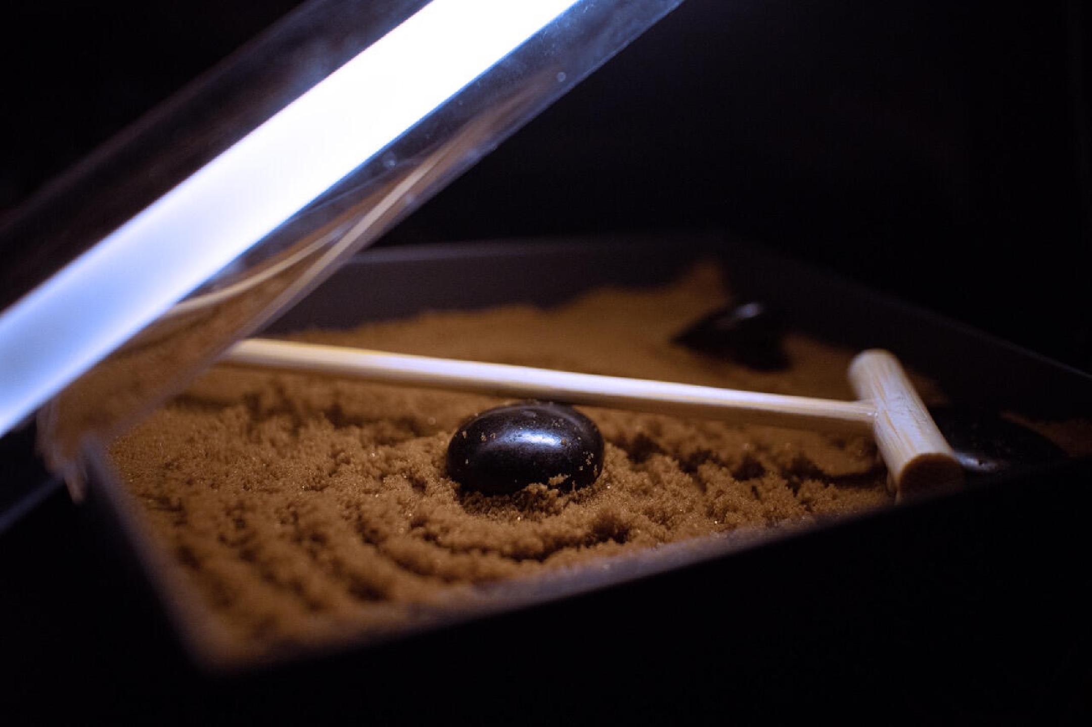 a small zen garden with two rocks in a box over a dark background illuminated by an LED strip